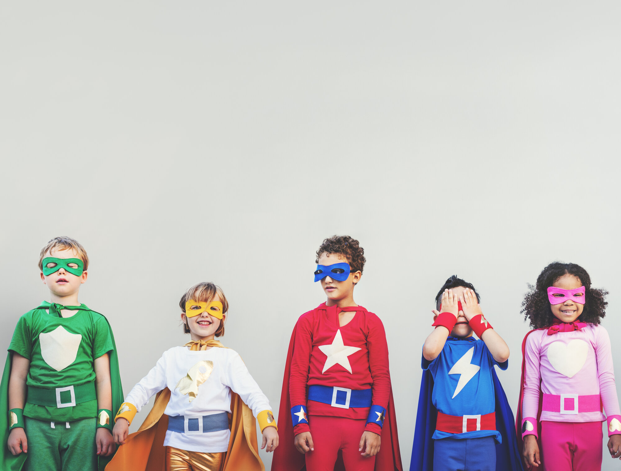 Five children wearing colourful superhero masks and capes